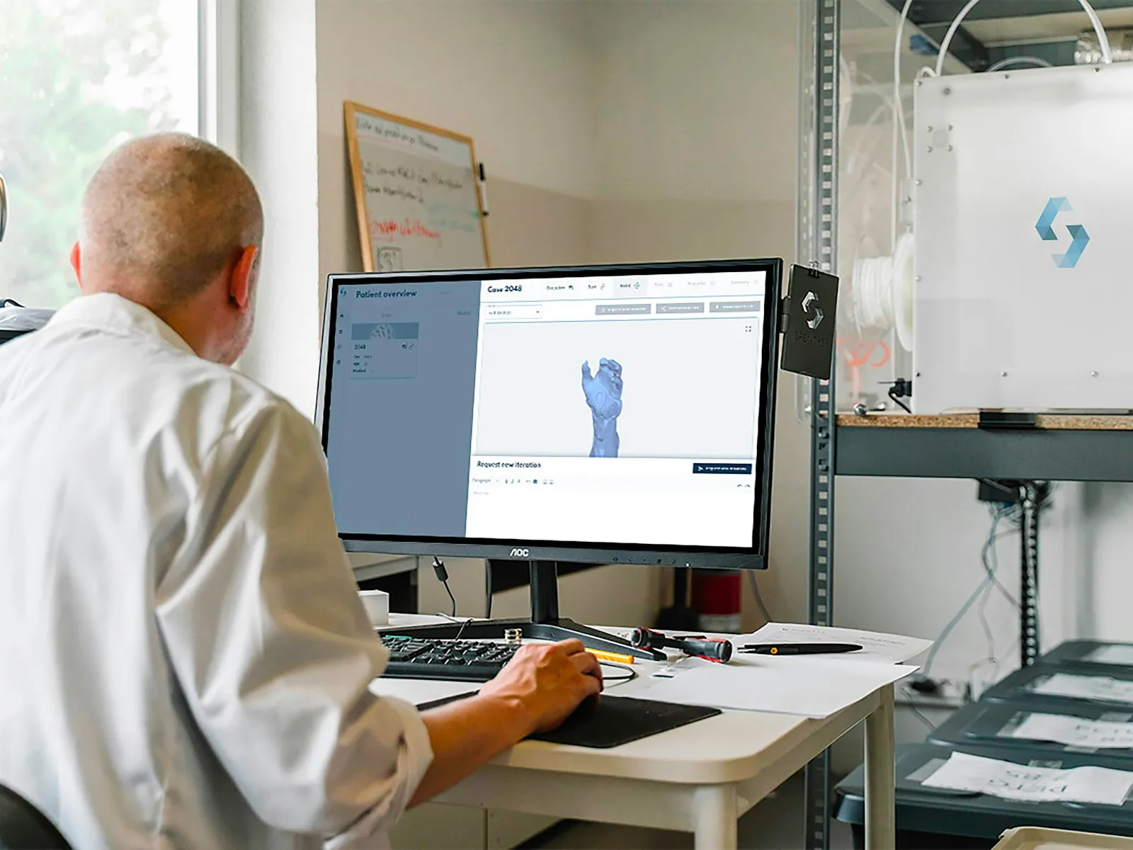 Eine Person bearbeitet ein räumliches Bauteil an einer technischen Arbeitsstation.