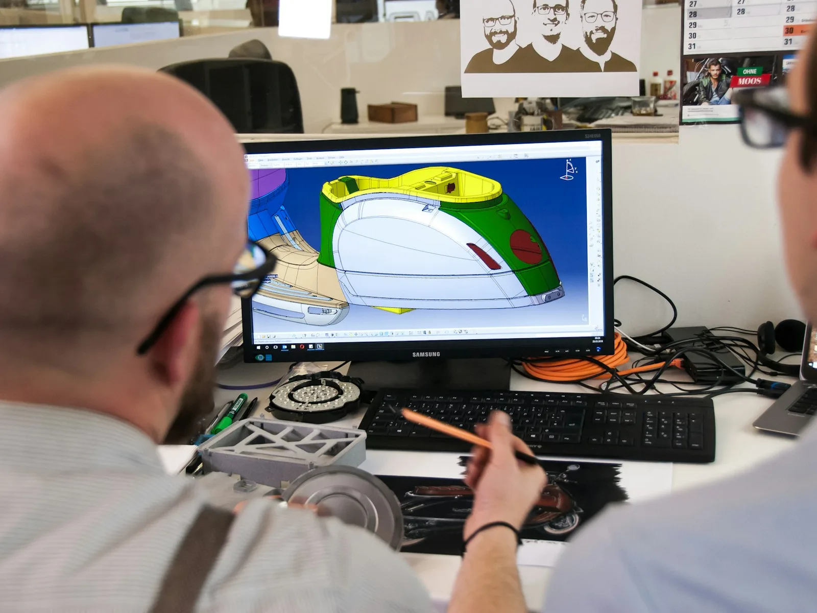 Person prüft ein technisches Produktmodell mit farblich hervorgehobenen Flächen am Bildschirm.