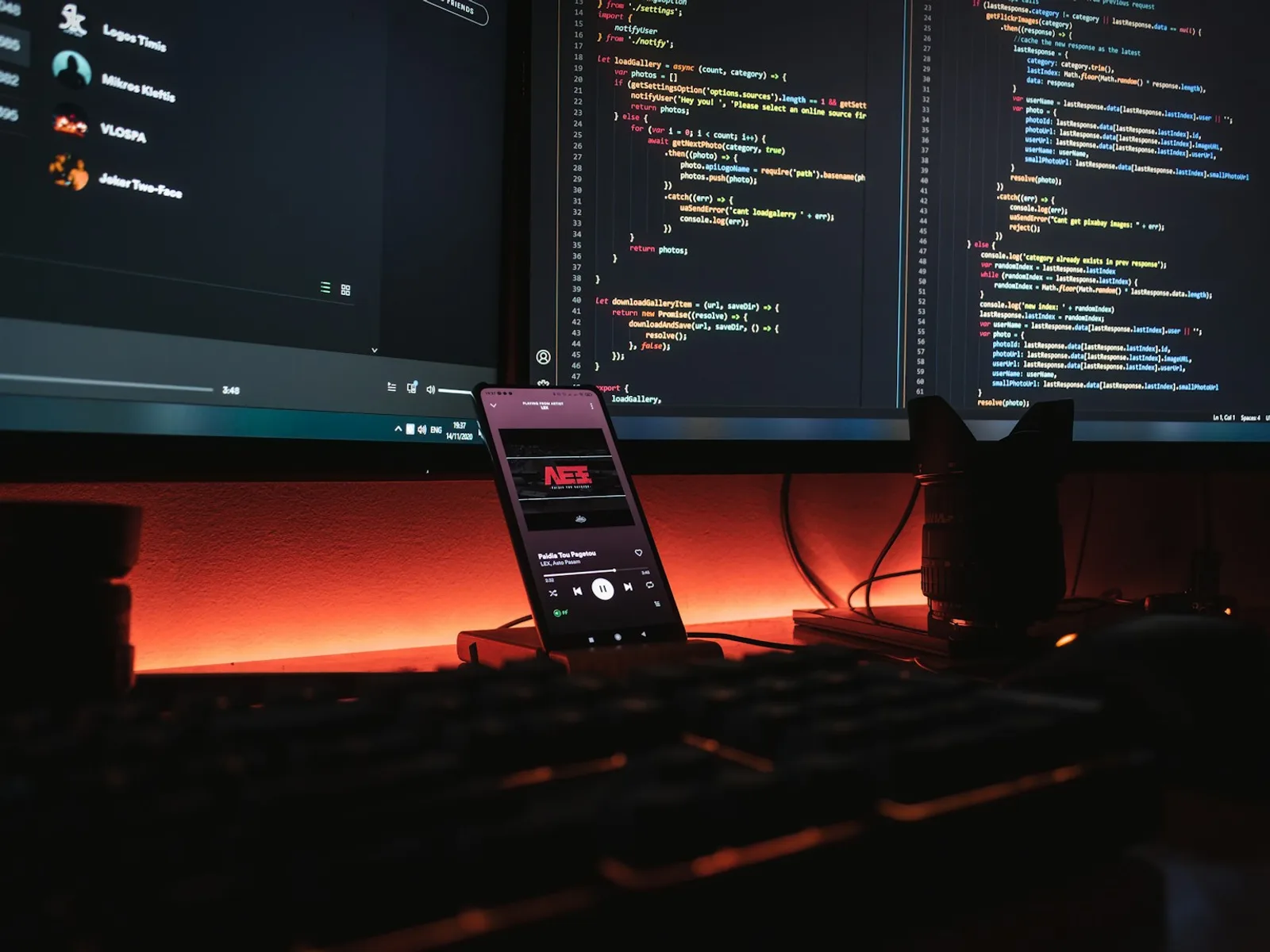 Mehrere Monitore mit Entwicklungsumgebung neben einem Smartphone.