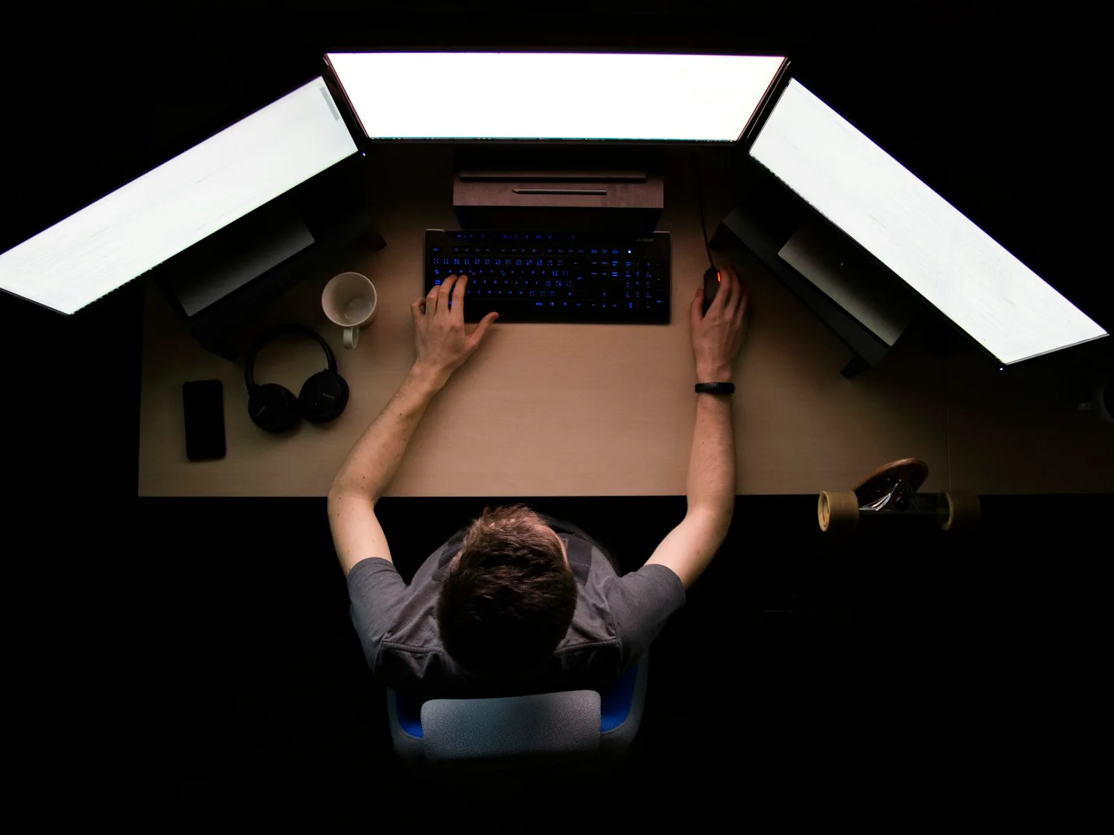 Blick von oben auf eine Person an einem Arbeitsplatz mit mehreren Monitoren.