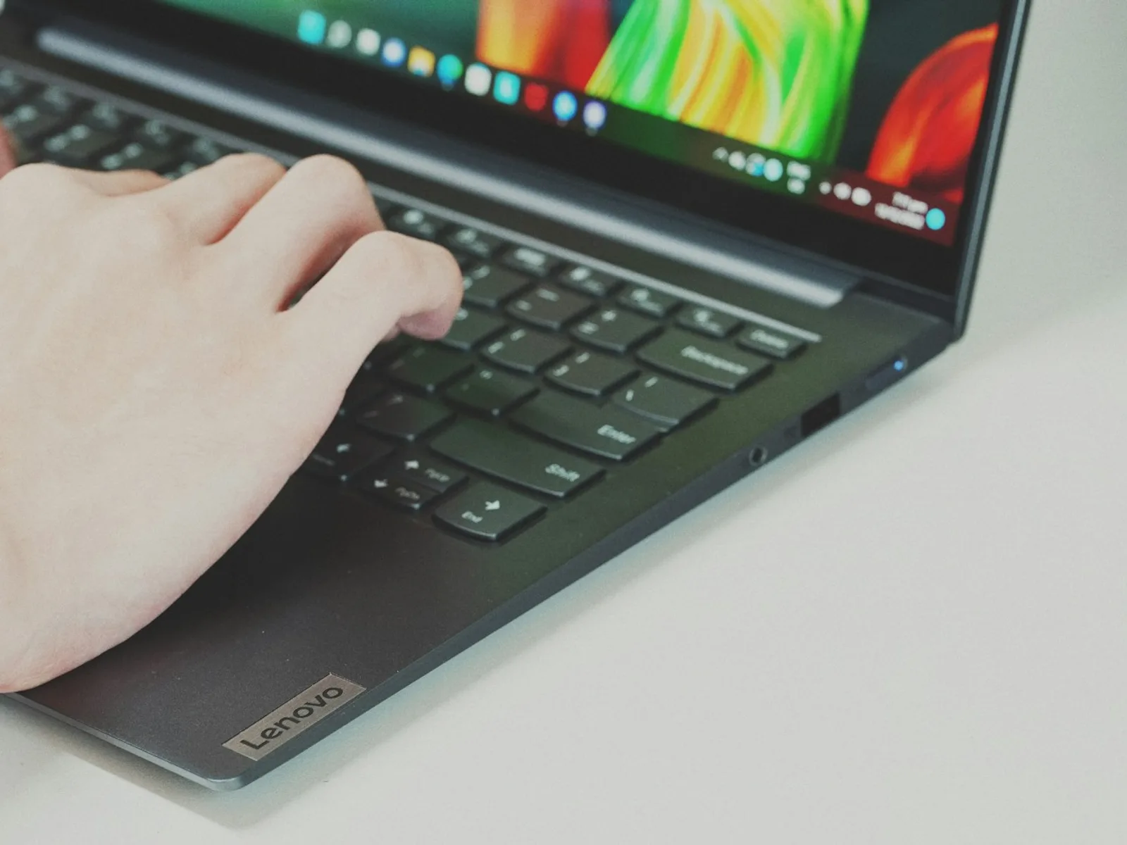 A person operates a dark laptop using its keyboard.