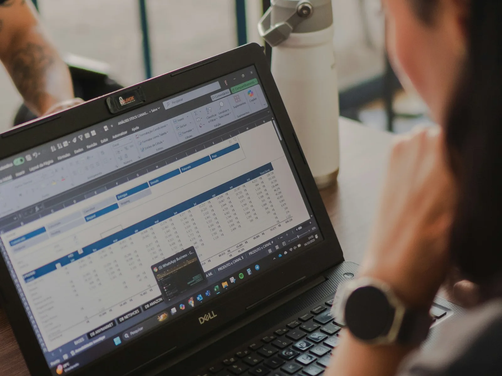 Eine Person prüft eine Tabelle mit Datenzeilen auf einem Laptop.