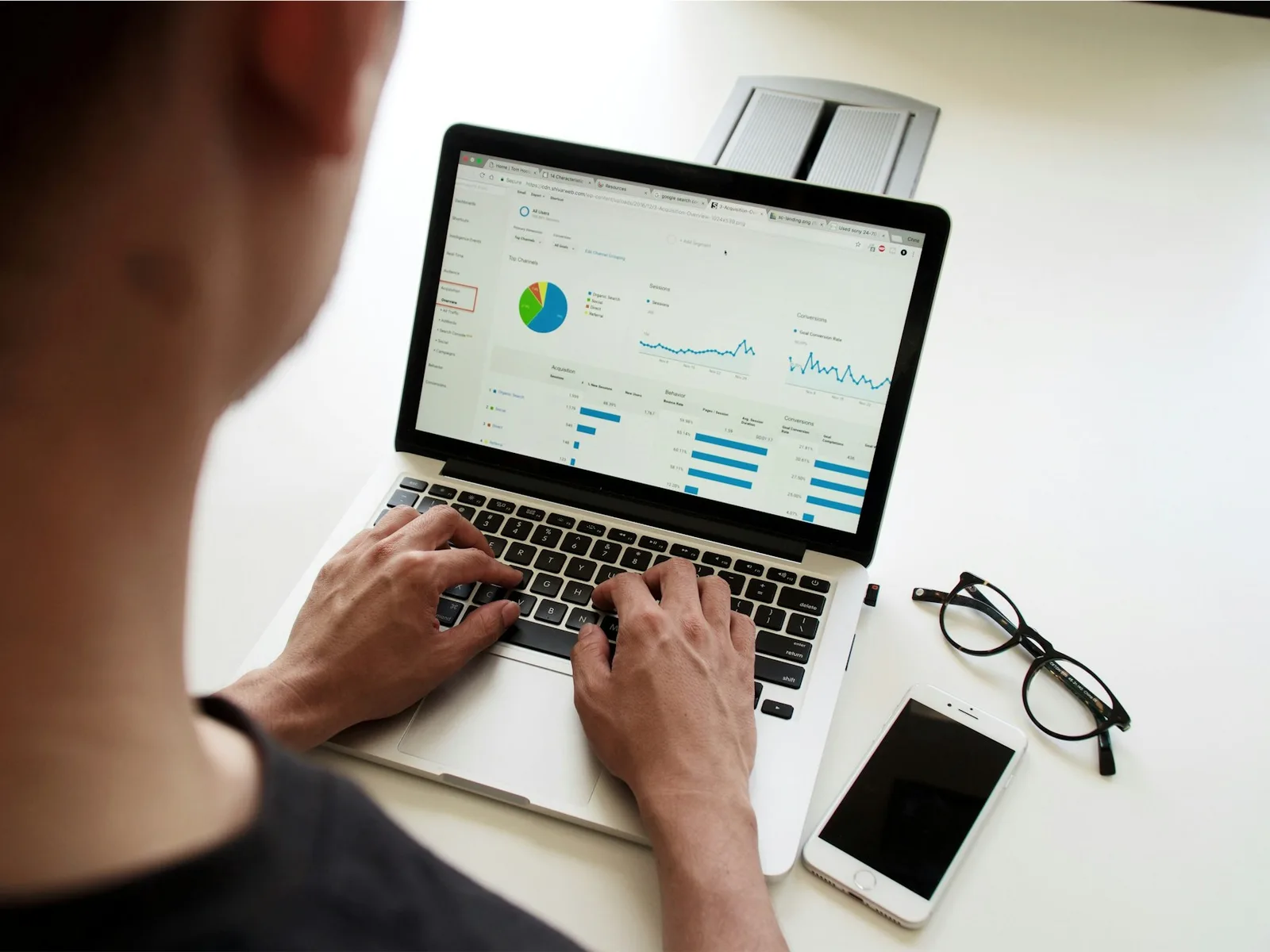 Eine Person prüft Diagramme und Datenübersichten in einer Anwendung am Laptop.