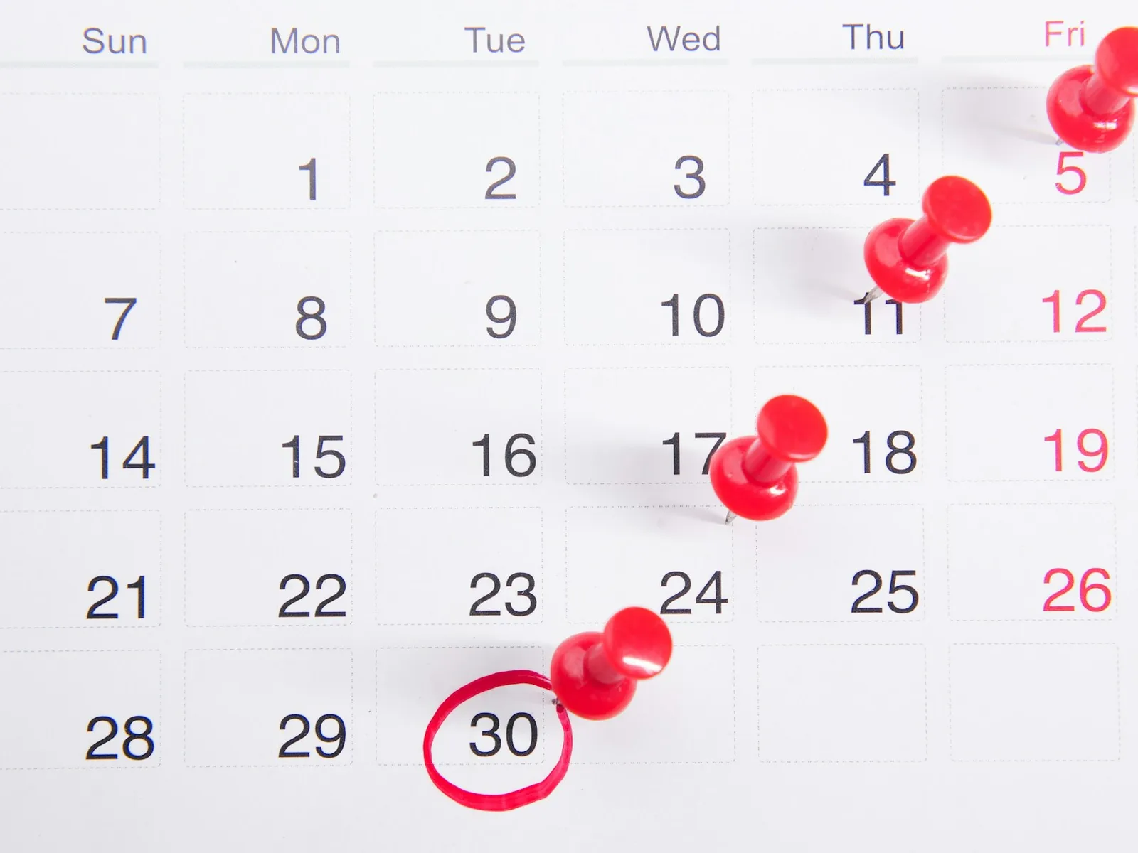 Kalender mit markierten Tagen und roten Stecknadeln.