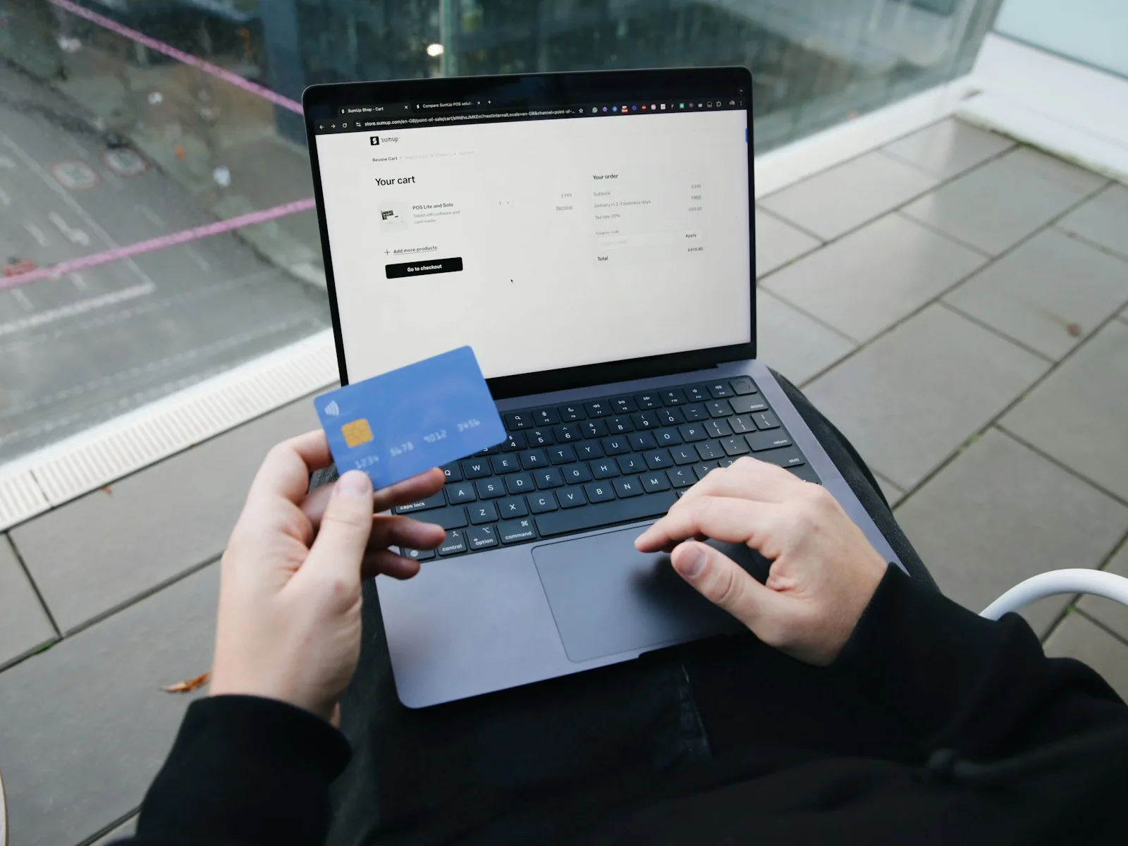 Person prüft eine Checkout-Seite auf dem Laptop und hält eine Zahlungskarte bereit.