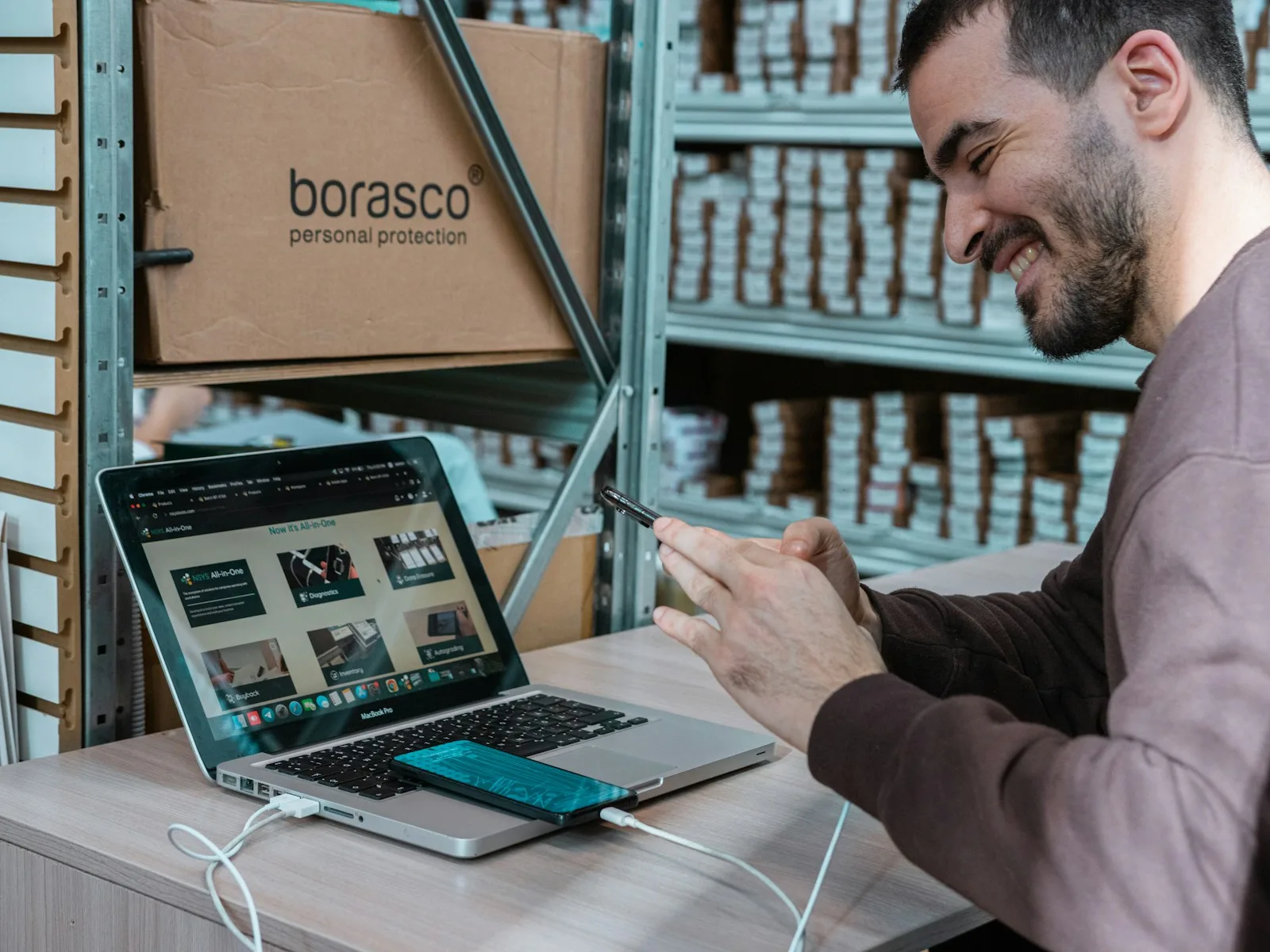 Ein Mitarbeiter prüft Geräte und Daten an einem Laptop im Warenbereich.