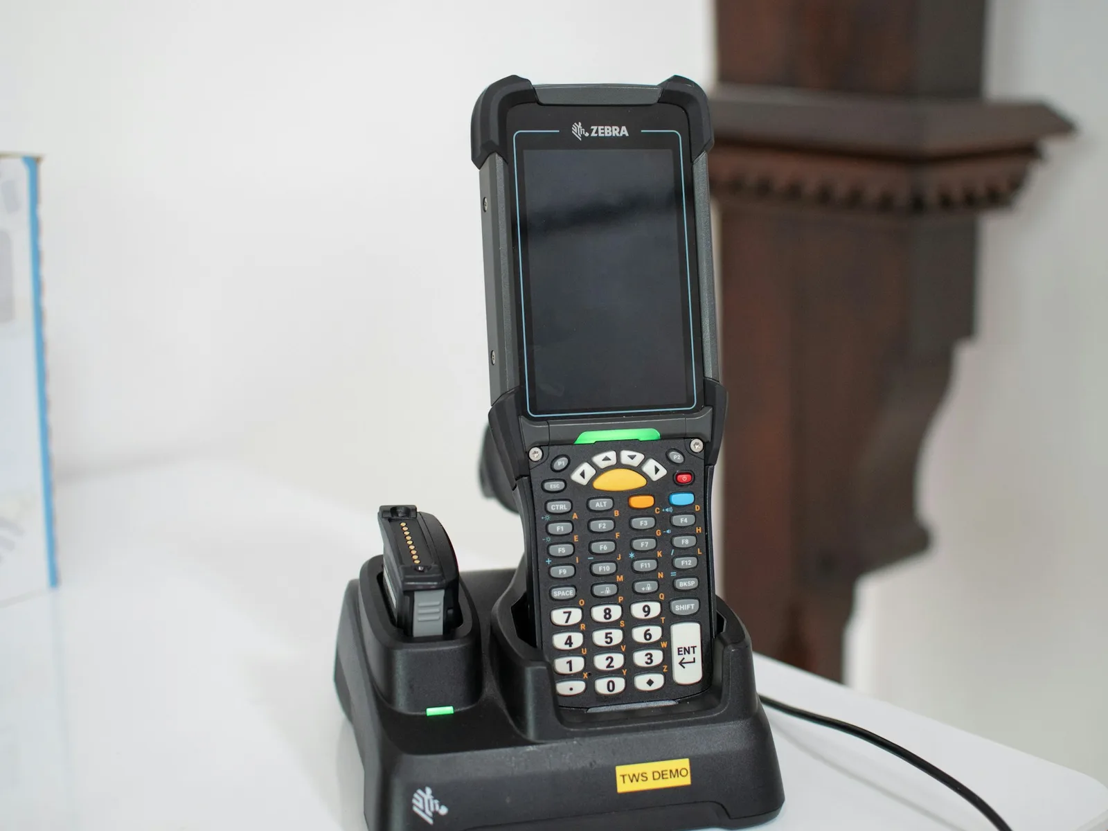 Ein Barcodescanner steht in seiner Ladestation auf einer Arbeitsfläche.