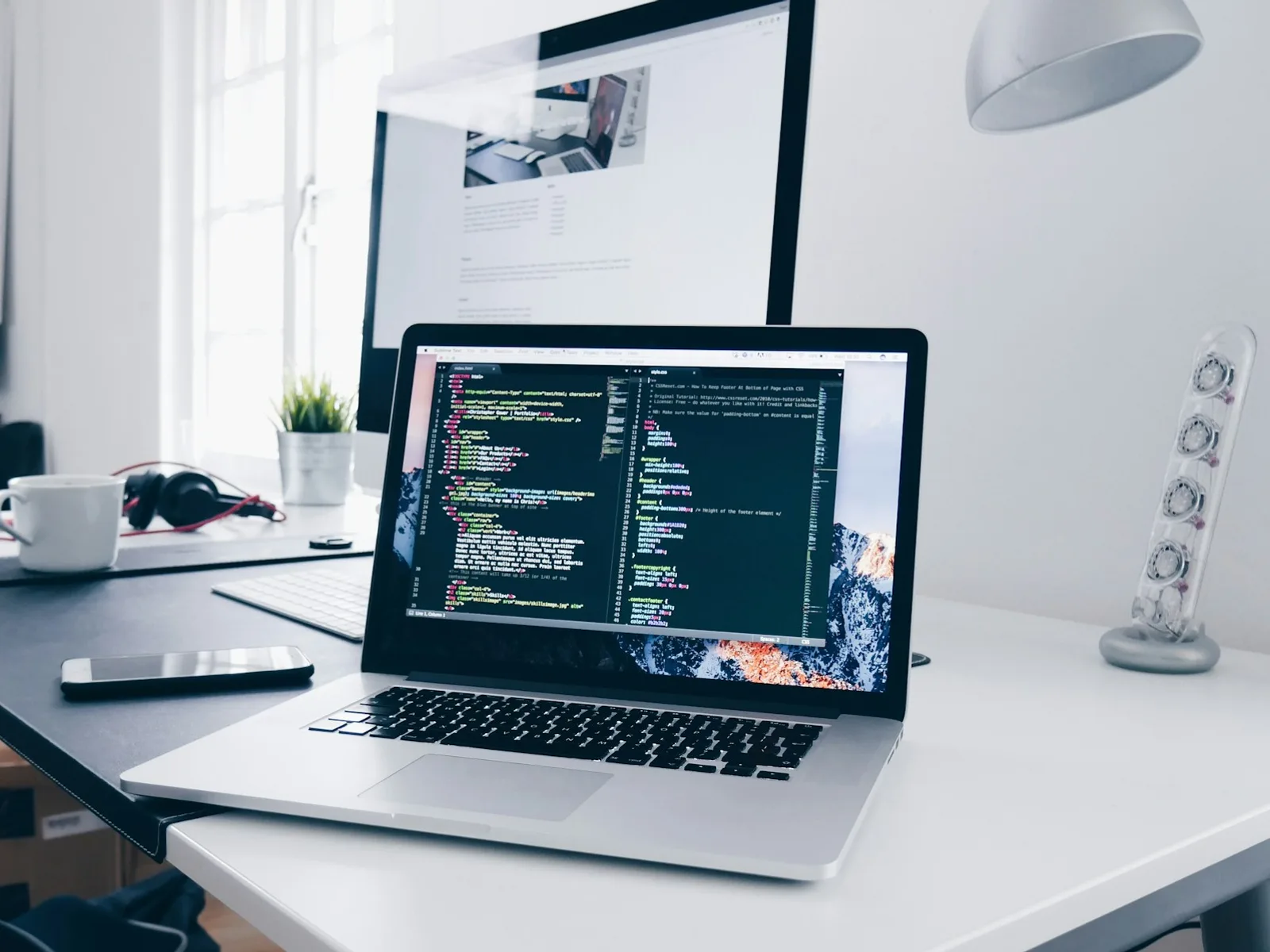 Laptop with an open development project on a light desk.