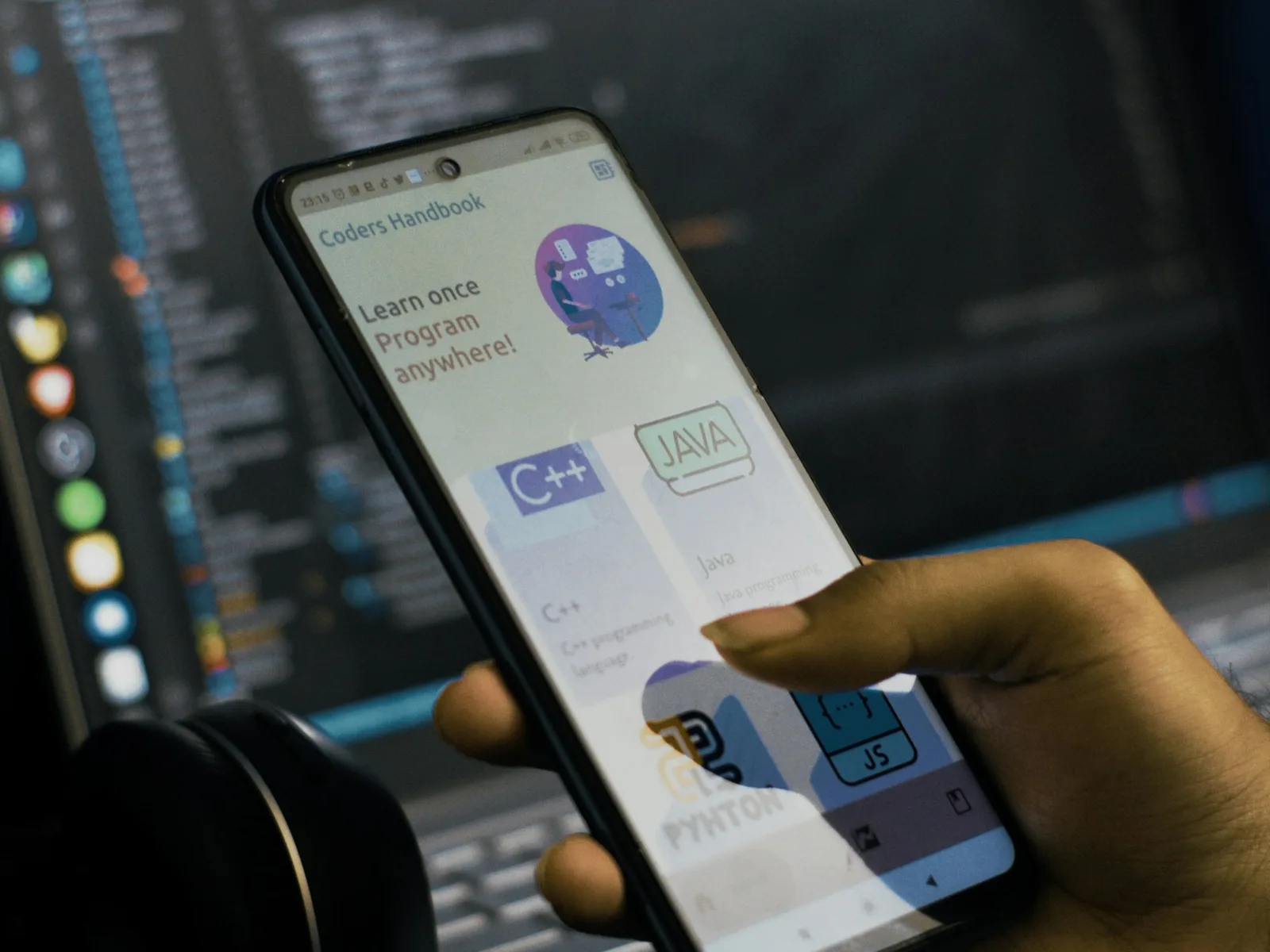 Hand prüft eine mobile Website auf dem Smartphone vor einem Laptop.