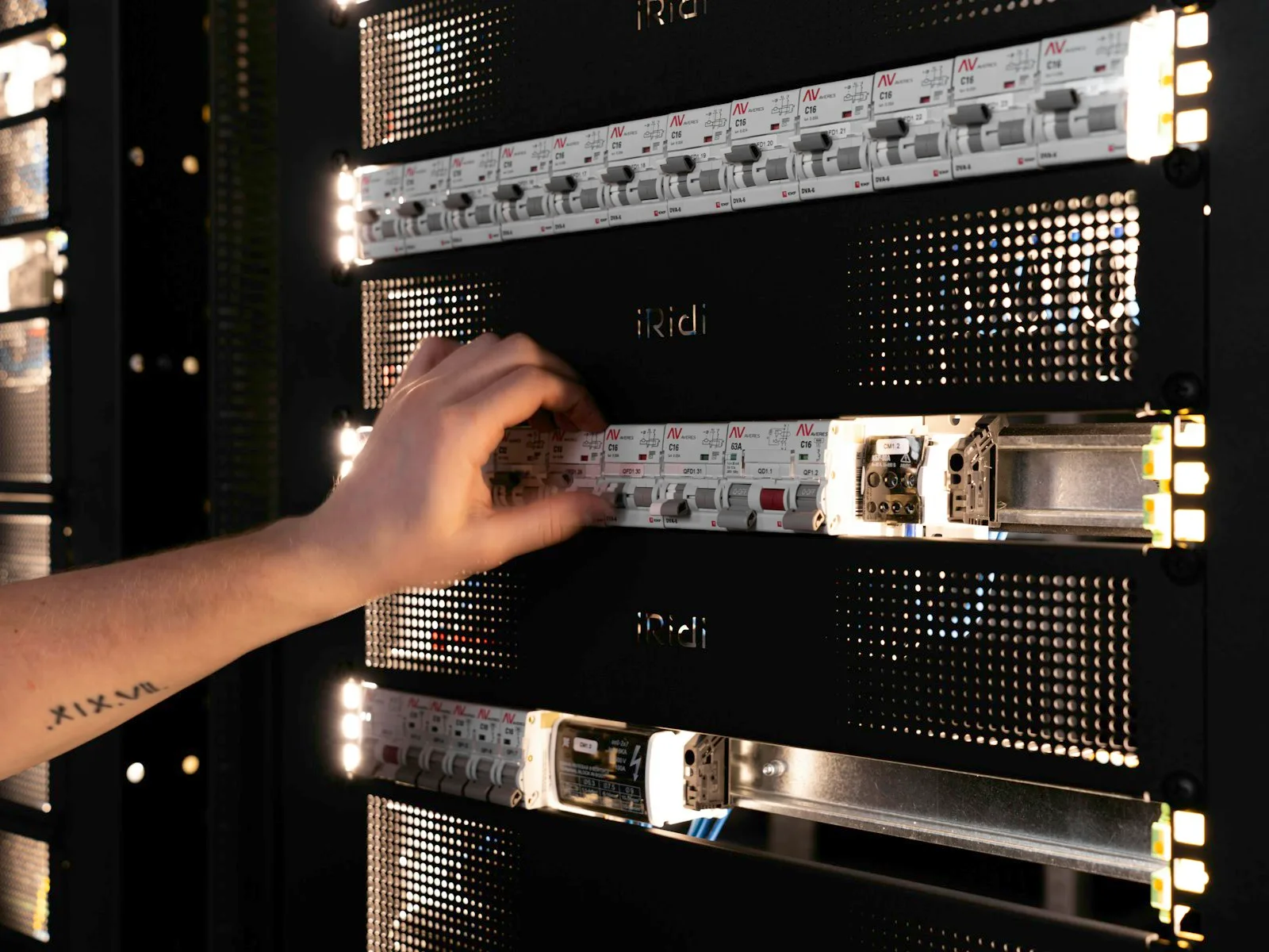 Hand überprüft Bauteile und Anschlüsse in einem geöffneten Serverrack.