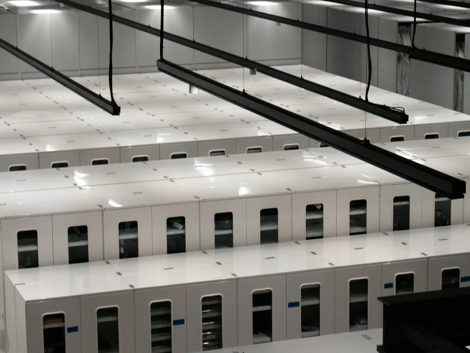 Heller Technikraum mit langen Reihen von Serverschränken.