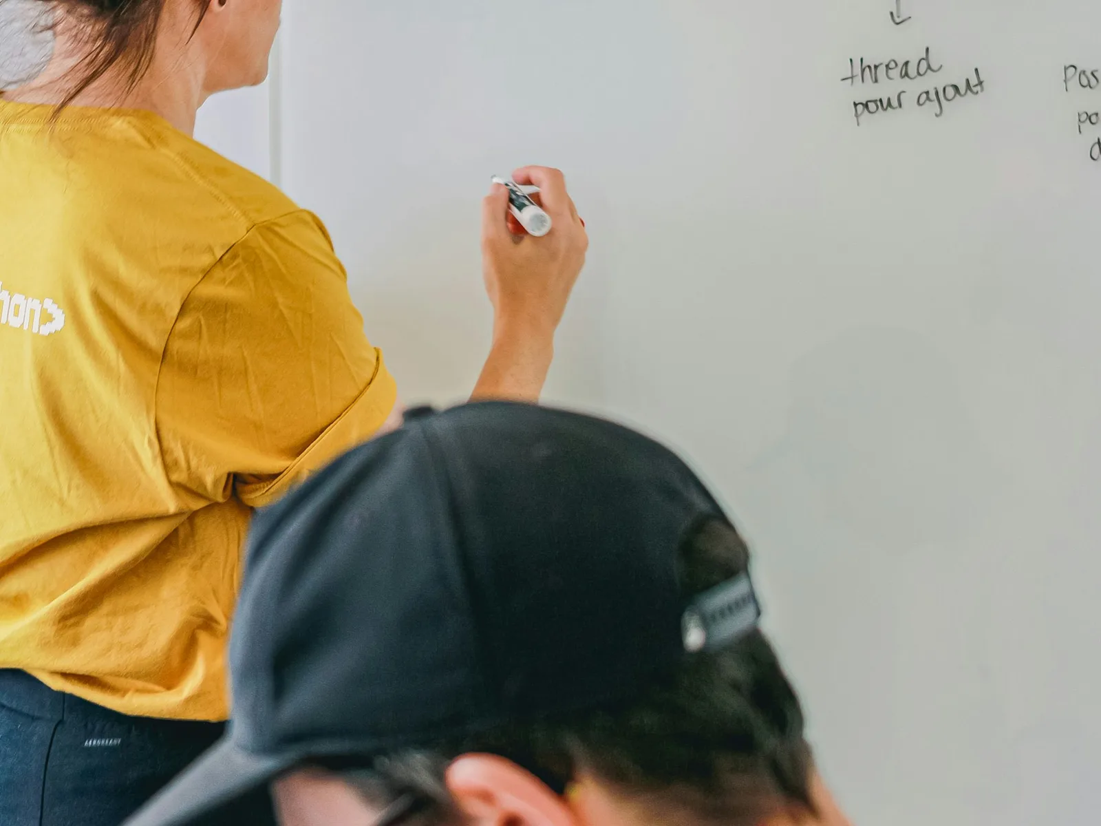 Zwei Personen entwickeln und besprechen Skizzen an einer beschreibbaren Wand.