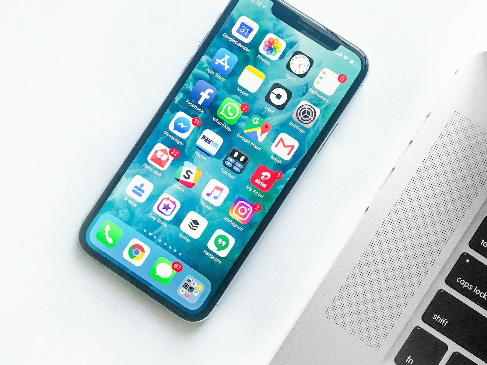 Smartphone mit einer Übersicht verschiedener Apps neben einer Laptop-Tastatur.
